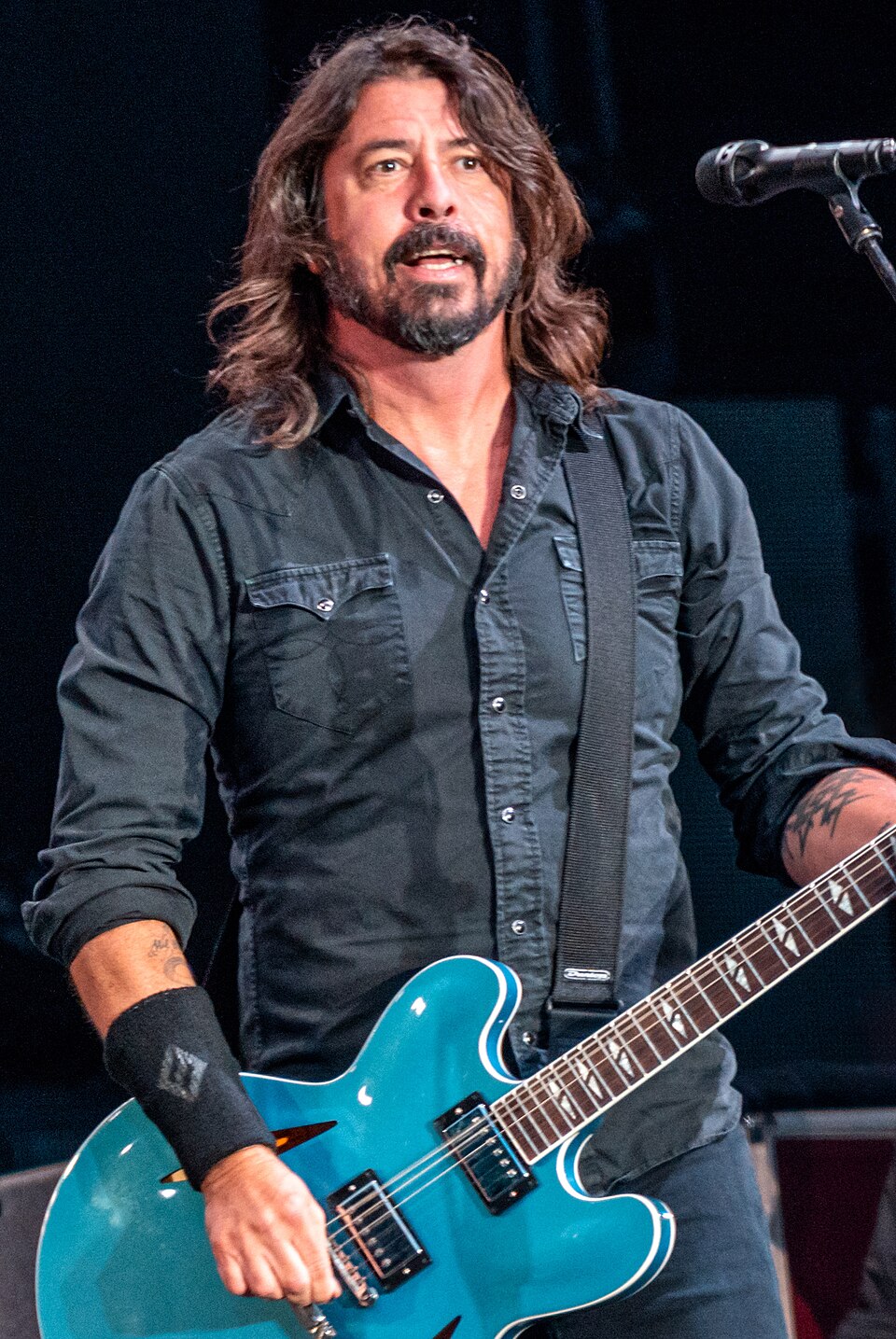 Dave Grohl on stage in Dublin in 2019, holding his blue Gibson guitar and addressing the crowd