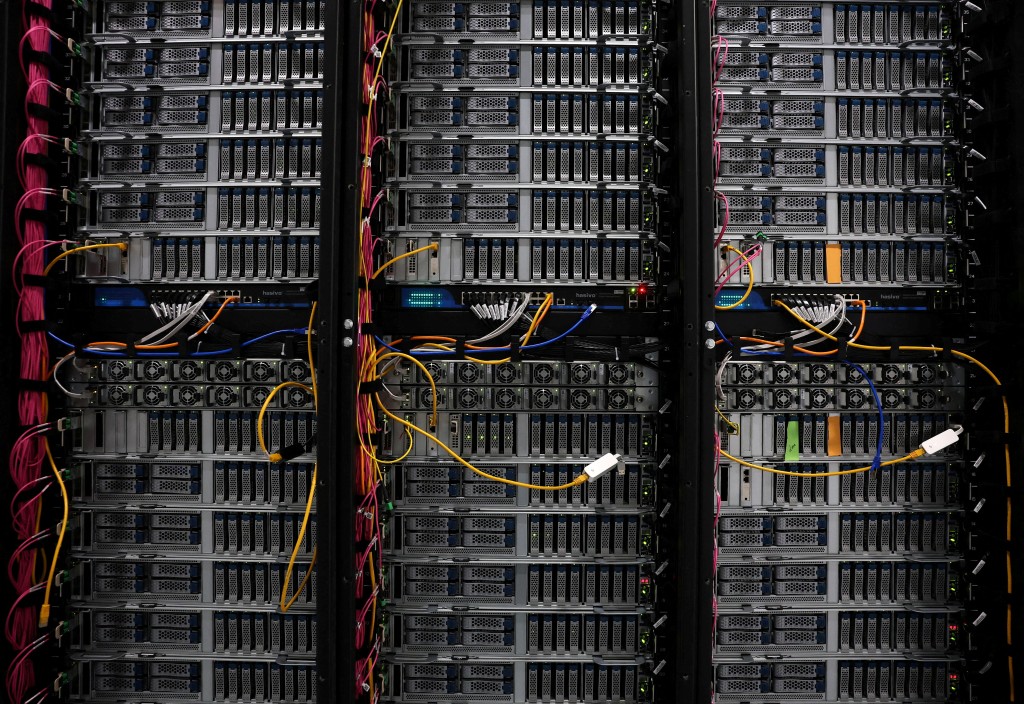 Rows of server racks inside an AI data center, glowing blue