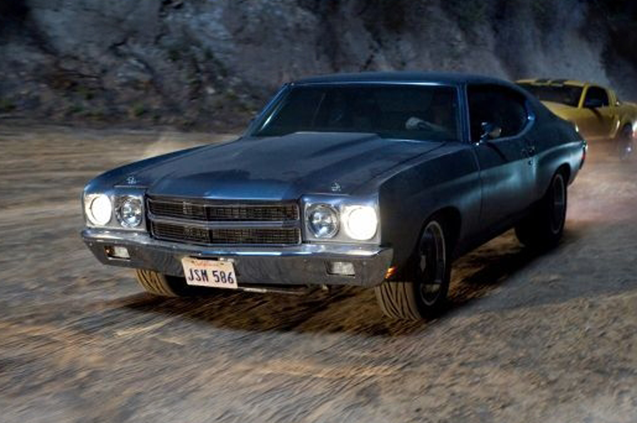 A classic muscle car from the Fast & Furious films racing on a dirt road