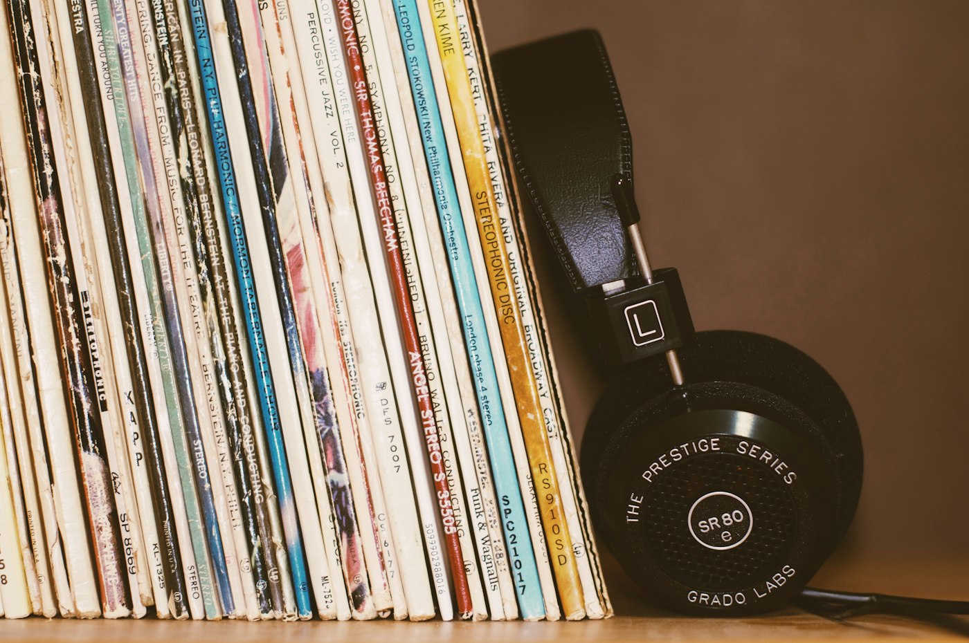 A phone and headphones on a bright desk with music playing