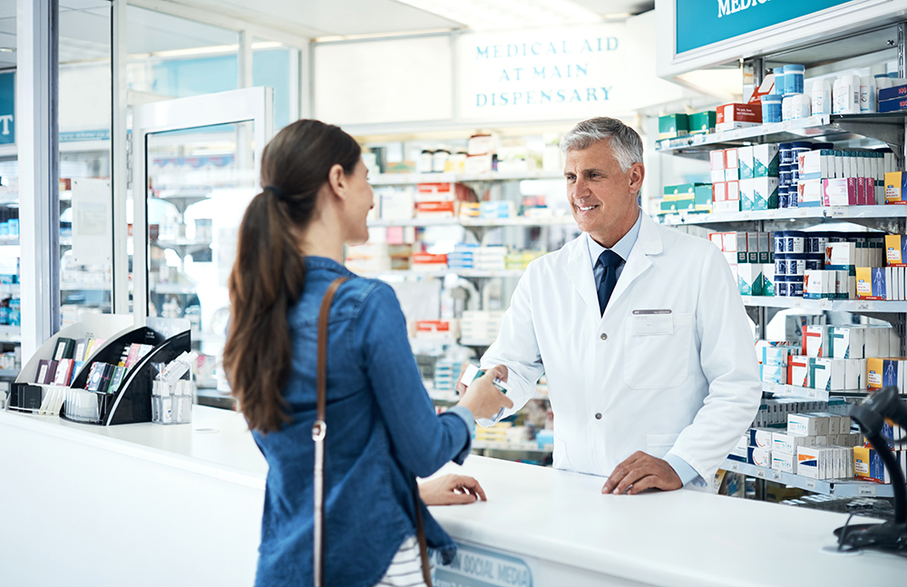 A pharmacist consulting a customer at a pharmacy counter