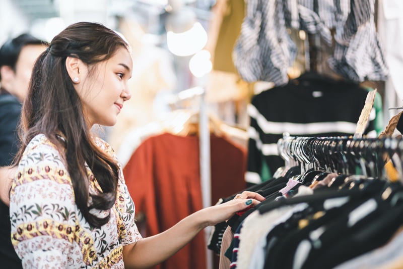 A shopper browsing clothing in a bright retail store