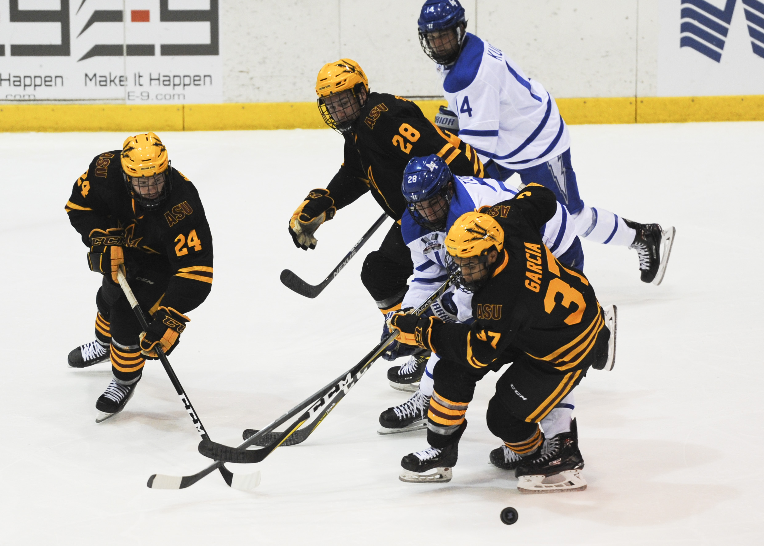 Sun Devils players in gold and black fighting for the puck against Air Force