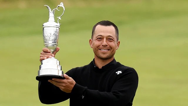 A golfer lifting a championship trophy in bright daylight.
