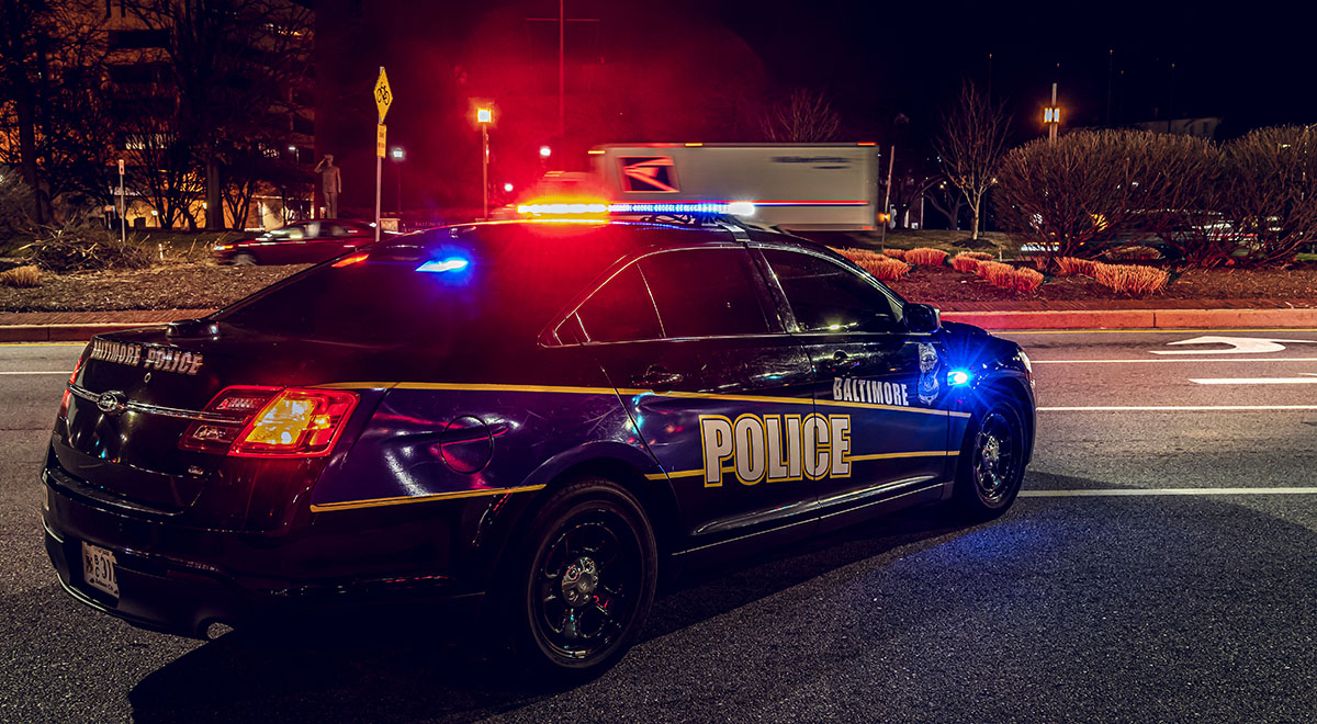 A Baltimore Police patrol car photographed at night with its emergency lights on