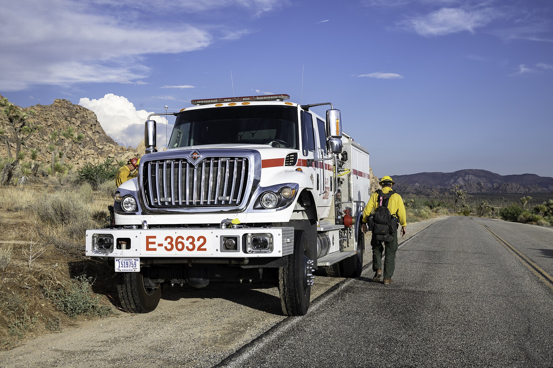 A wildland fire engine and firefighters on a sunny Southern California road