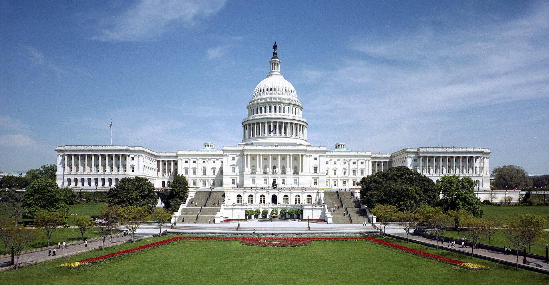 The U.S. Capitol west front in daylight, with tulip beds on the lawn in front