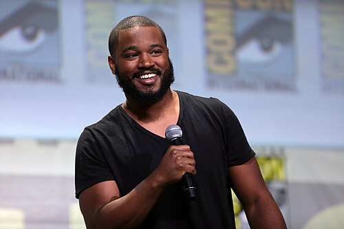 Ryan Coogler on stage at San Diego Comic-Con, holding a microphone