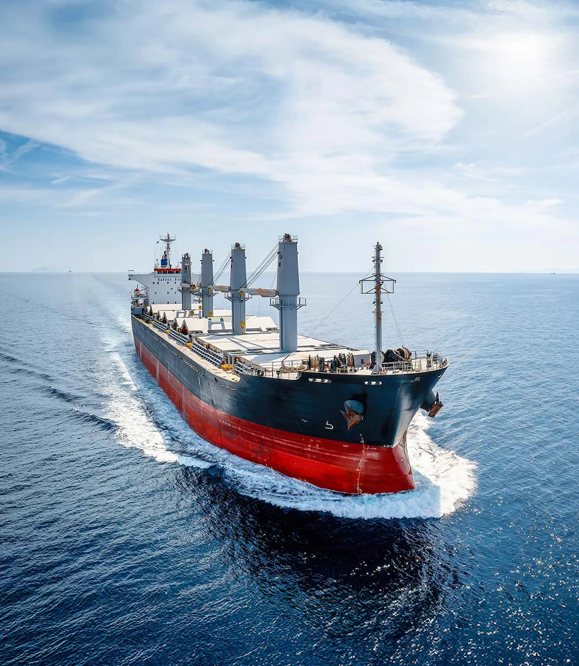 A bulk carrier vessel underway at sea in daylight