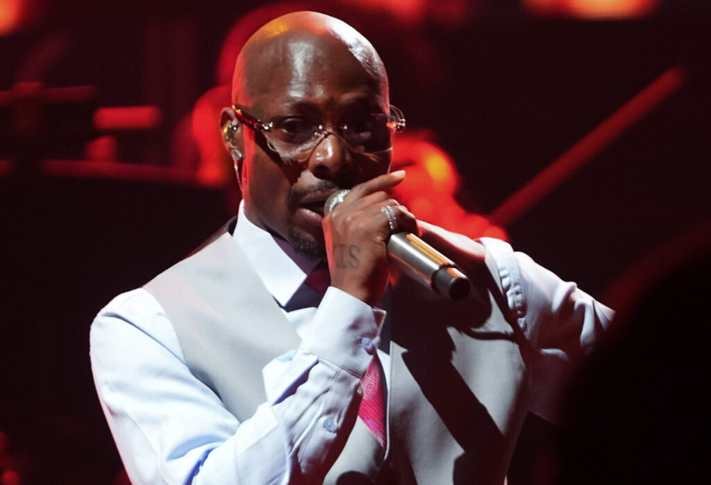 Asake performing live on stage, gripping a microphone