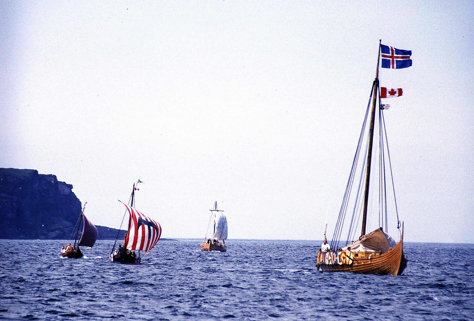 Replica Viking ships under sail on open water in daylight