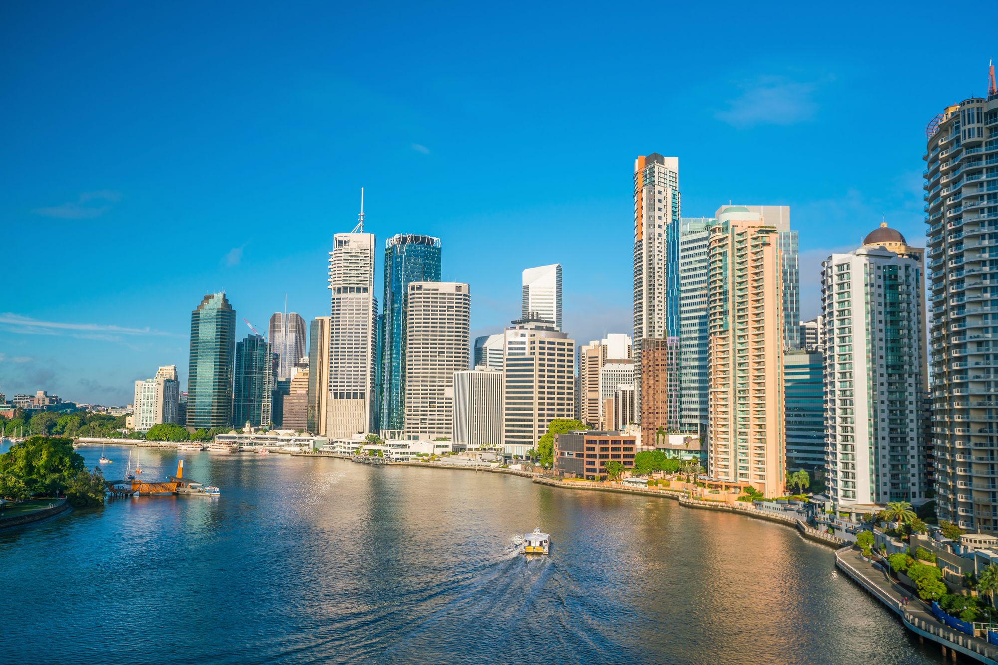 The Brisbane skyline along the Brisbane River on a bright day — the host city of the 2032 Olympic and Paralympic Games.