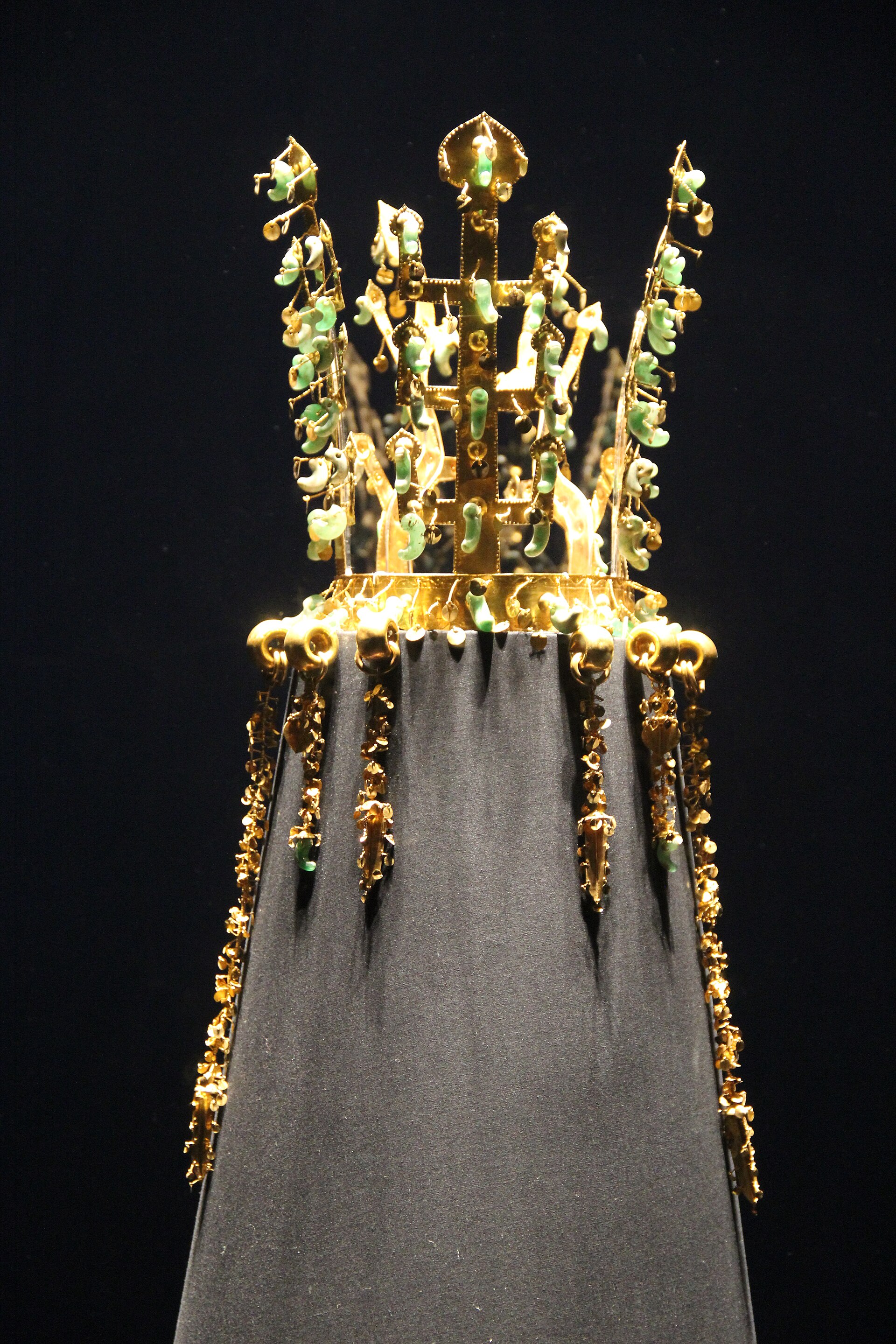 A gold crown of the Silla kingdom with dangling jade pendants, lit in a museum case