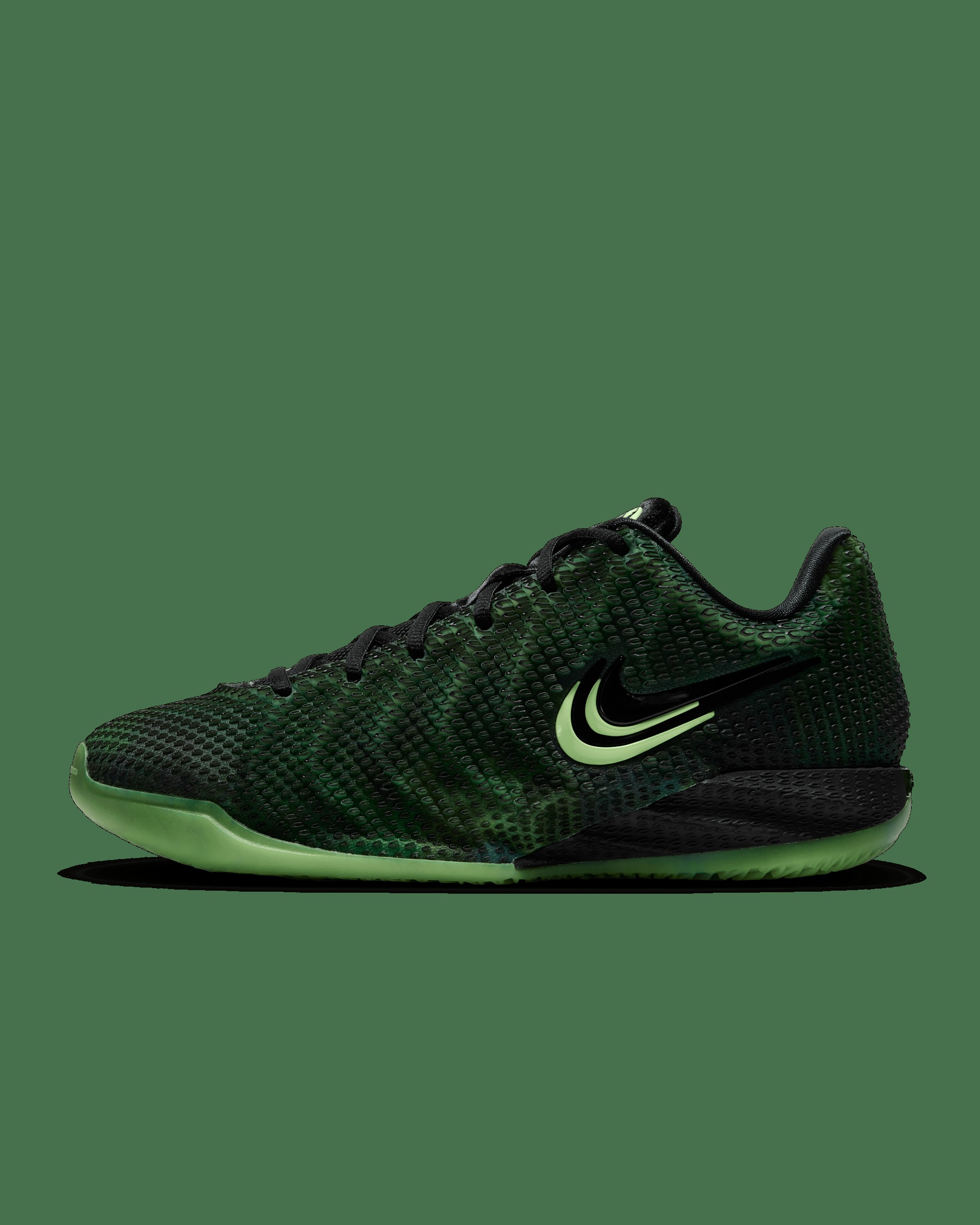 The Nike Caitlin 1 Jinx (JA4290-001) in profile — black knit upper with Ghost Green accents and glow-in-the-dark sole, on Nike's green studio background