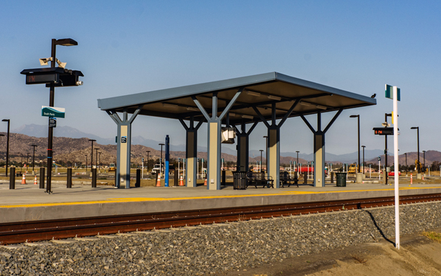 Metrolink station platform with a covered shelter and mountains in the distance