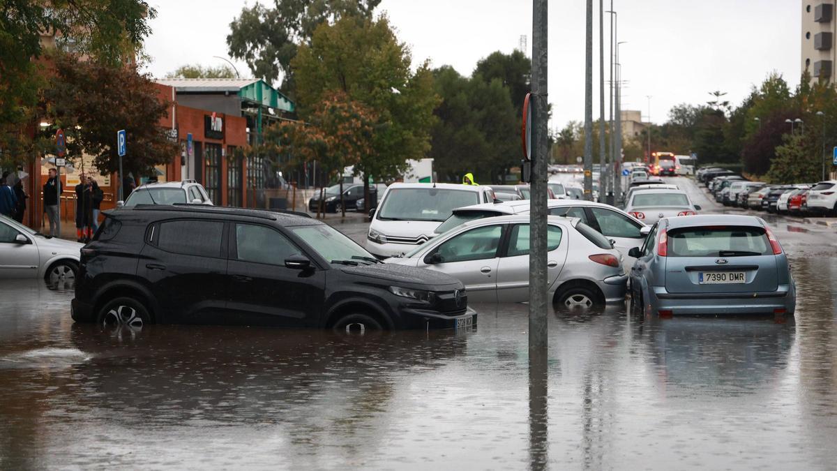 Parked cars with wheels submerged in floodwater on a flooded street in Catalonia