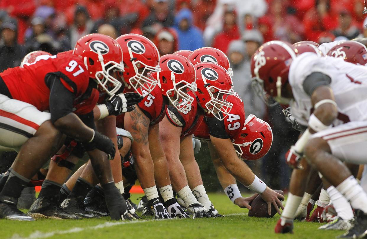 Georgia and Alabama linemen at the line of scrimmage, Georgia’s red G helmets against Alabama’s crimson