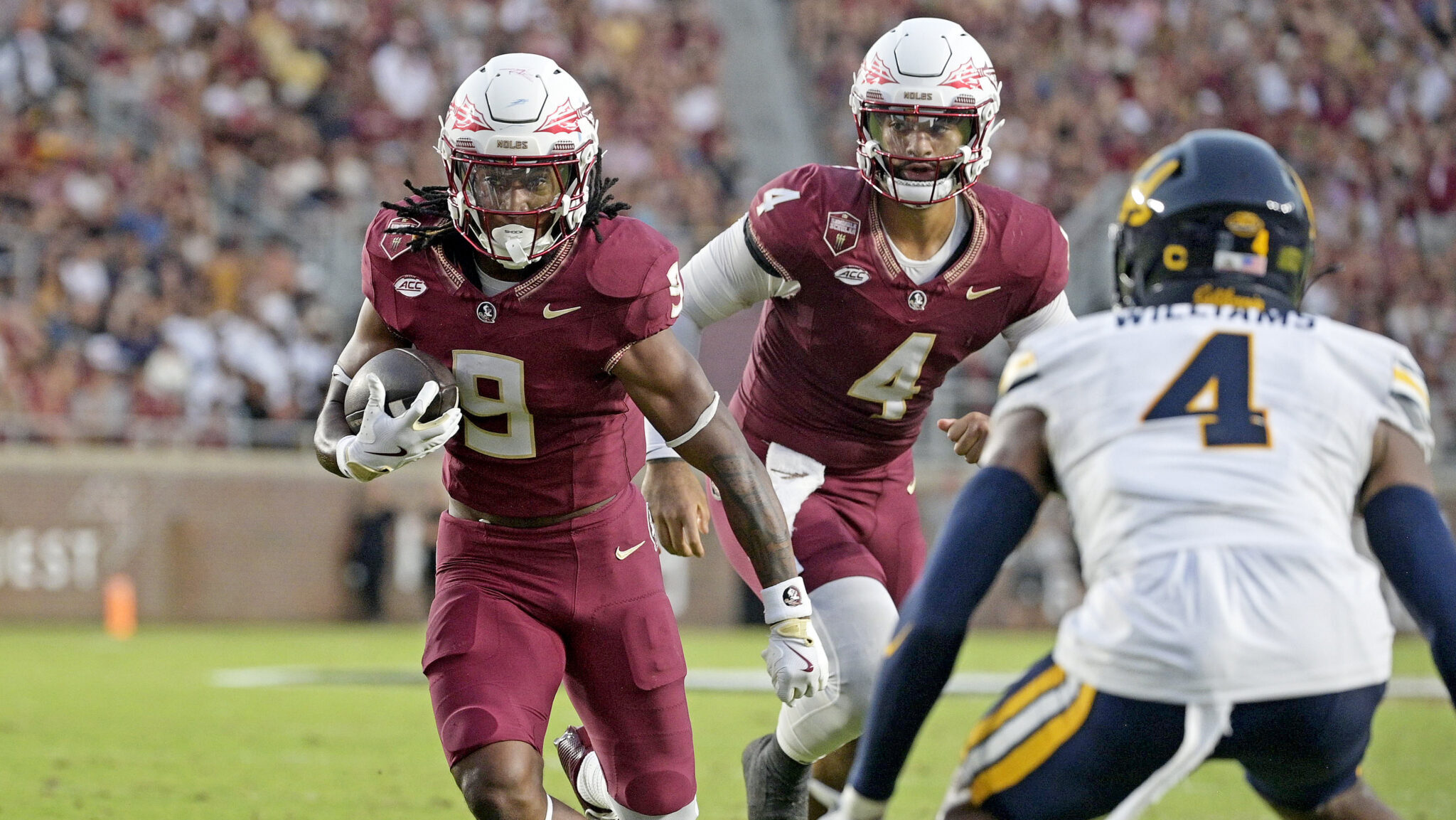 Florida State Seminoles in garnet uniforms running with the football during game action