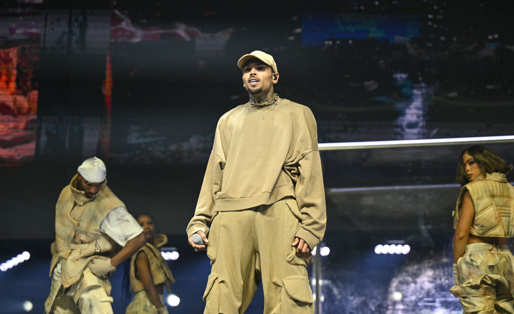 Chris Brown performing onstage during a concert, with dancers behind him.