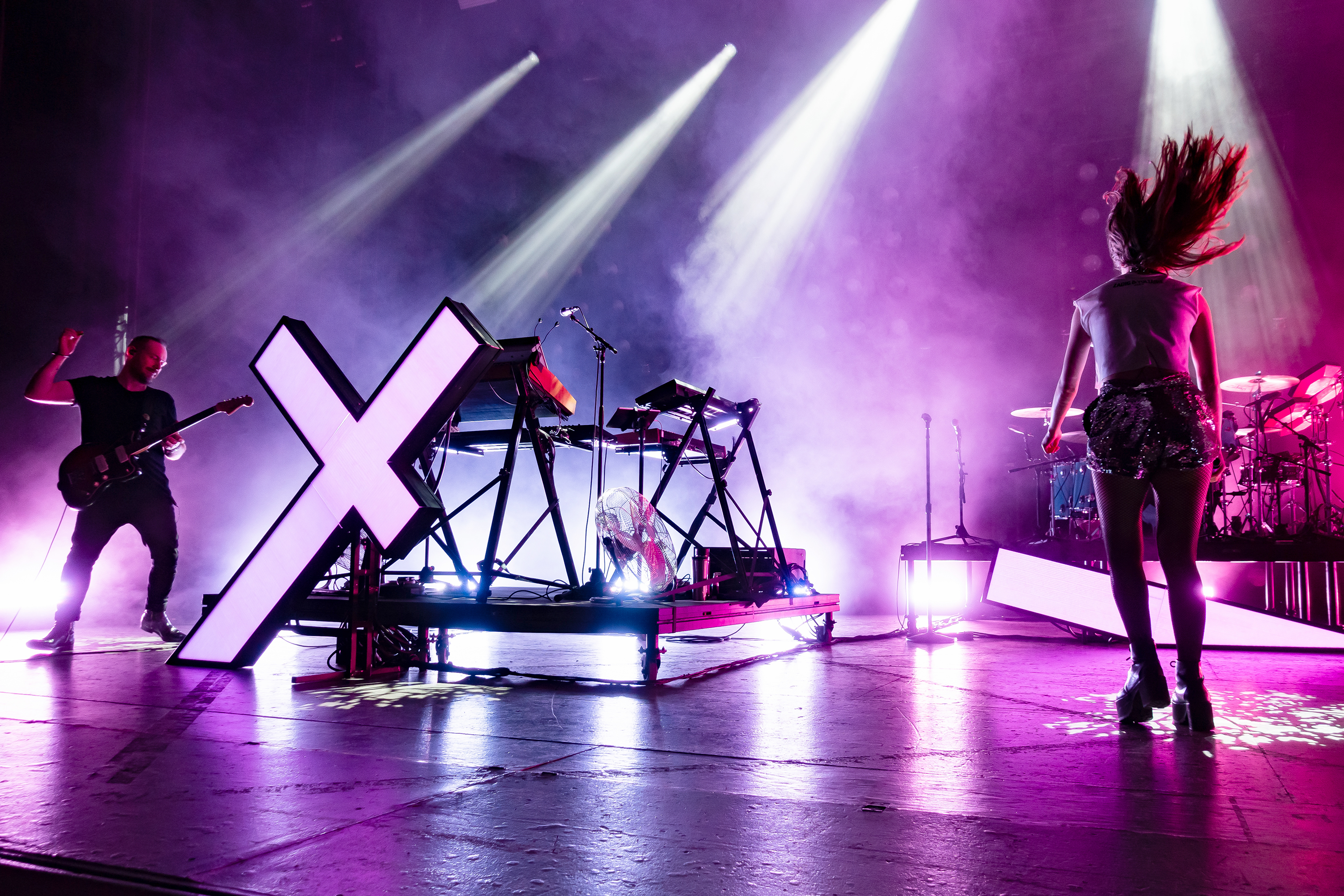 Chvrches performing live on stage in bright stage light