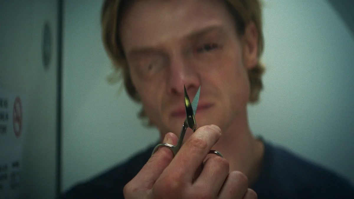 Tom Rhys Harries as Matt Hagen in Clayface — face deforming, holding scissors toward the lens, in the film's released signature still