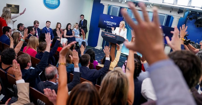 Reporters raise hands in the White House briefing room