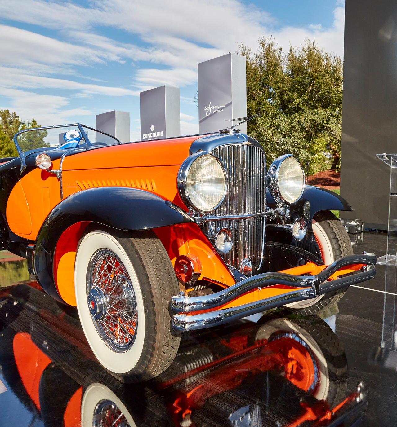 An orange and black pre-war American classic on the glossy Winner's Circle stage at a prior Concours at Wynn — event file photography