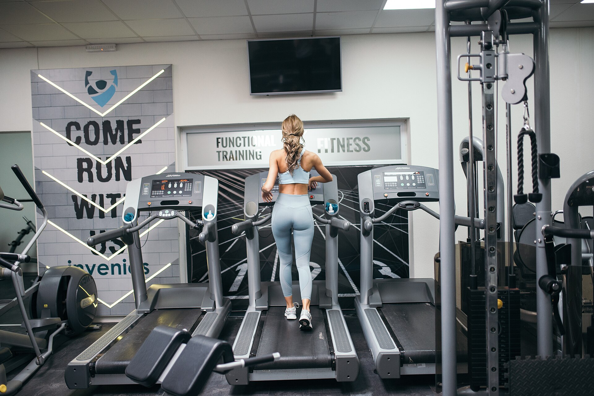 A woman running on a treadmill in a bright, modern gym