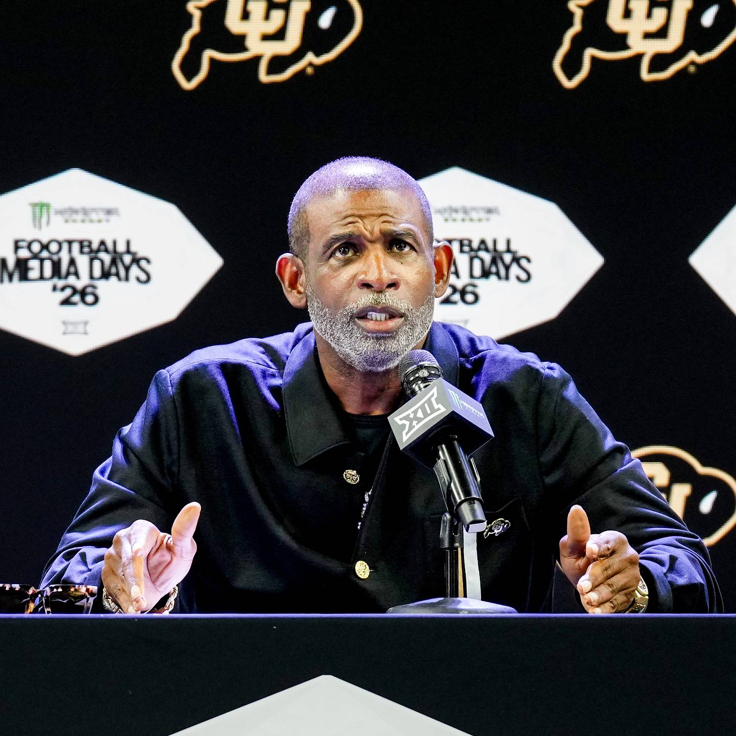 Deion Sanders speaking at a podium during Big 12 Media Days