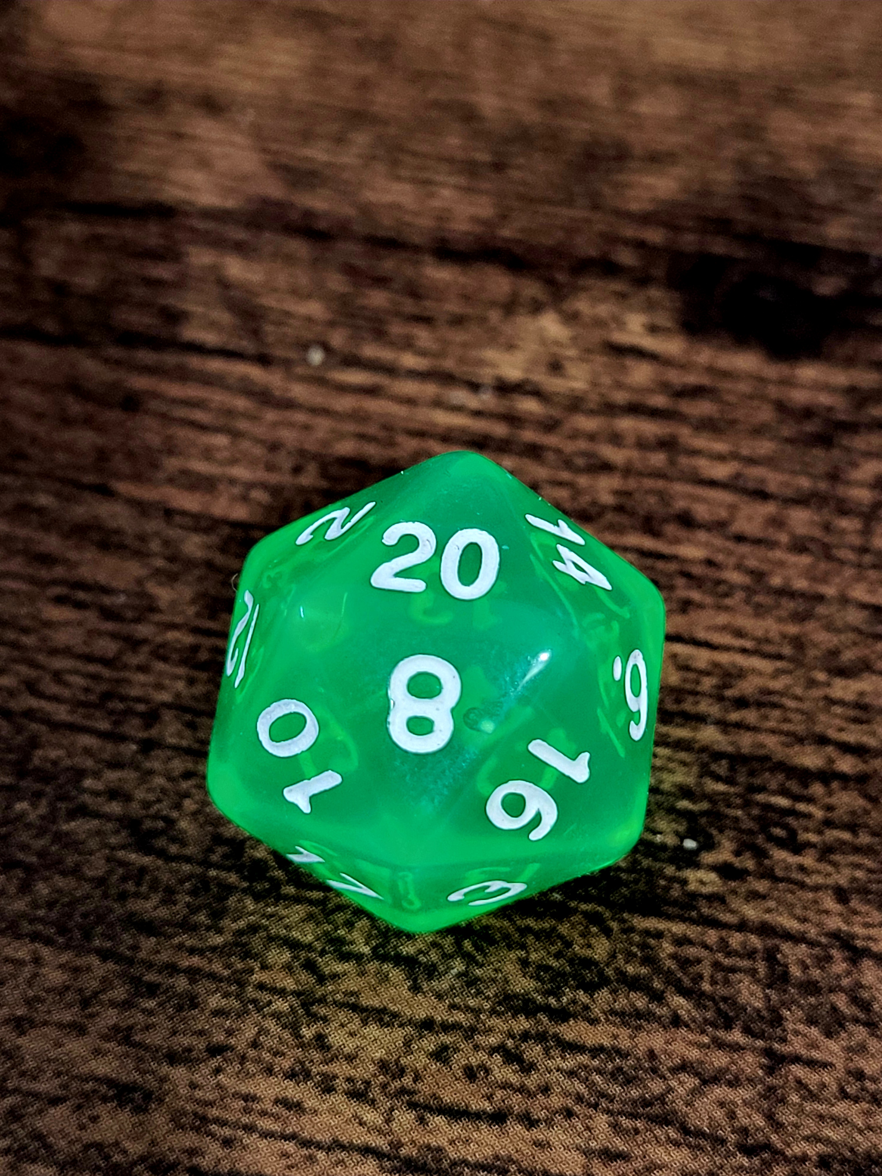 A bright green twenty-sided die showing a natural 20 on a wooden table