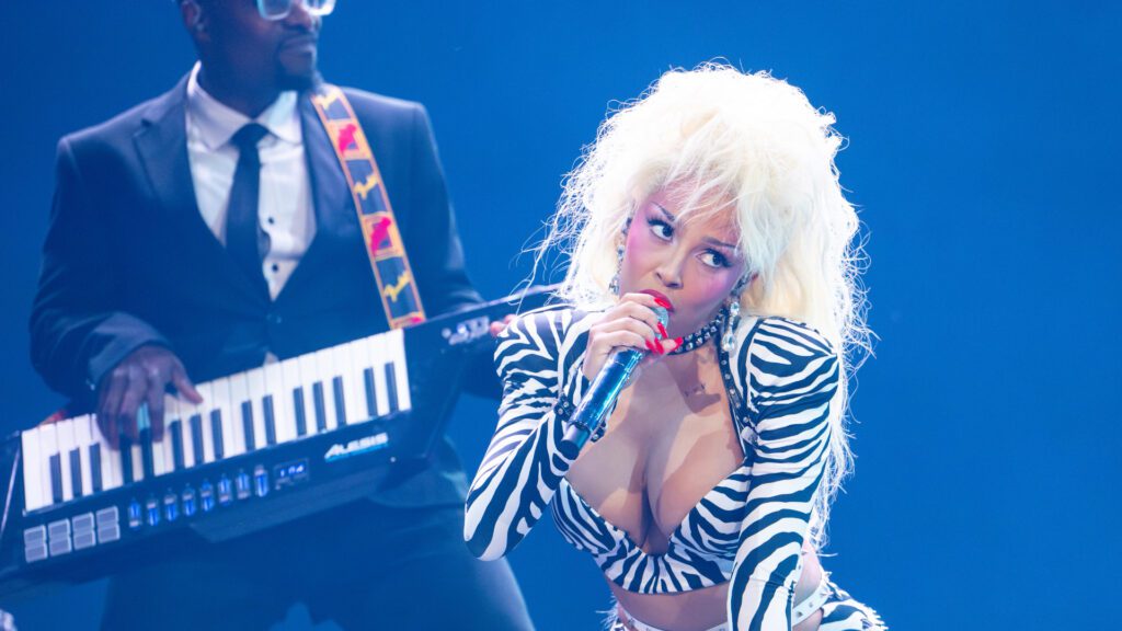 Doja Cat performing on stage with a keyboardist during a live show