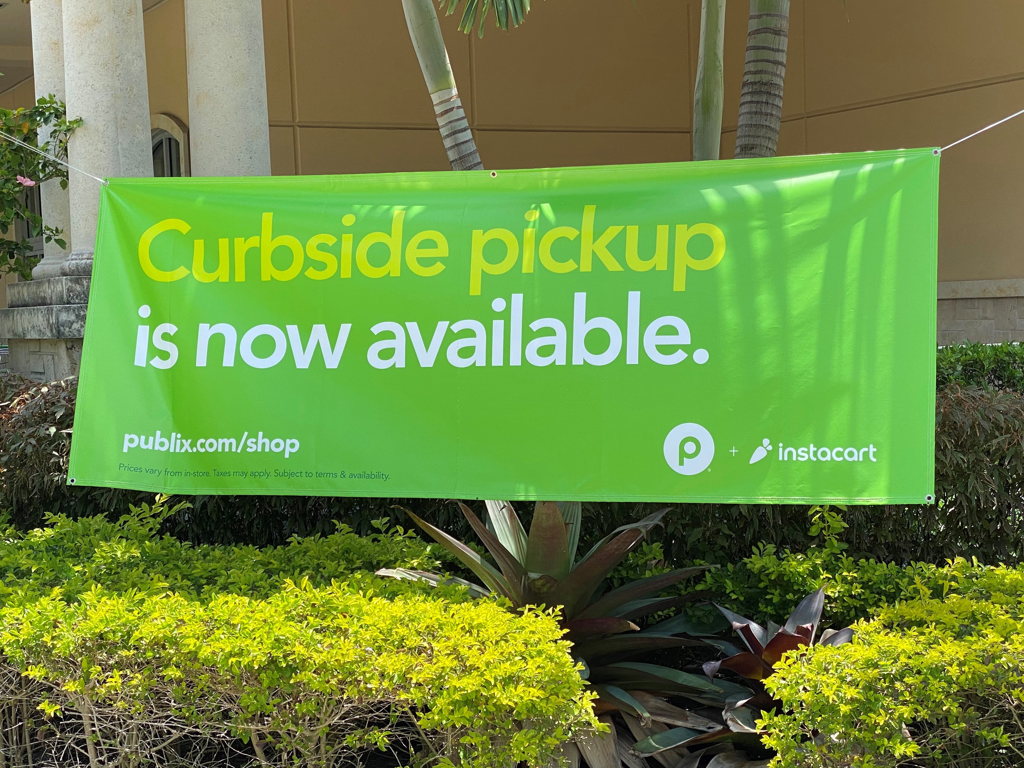 A green Instacart 'Curbside pickup is now available' banner carrying the Publix and Instacart logos at a Publix grocery store in West Miami, Florida