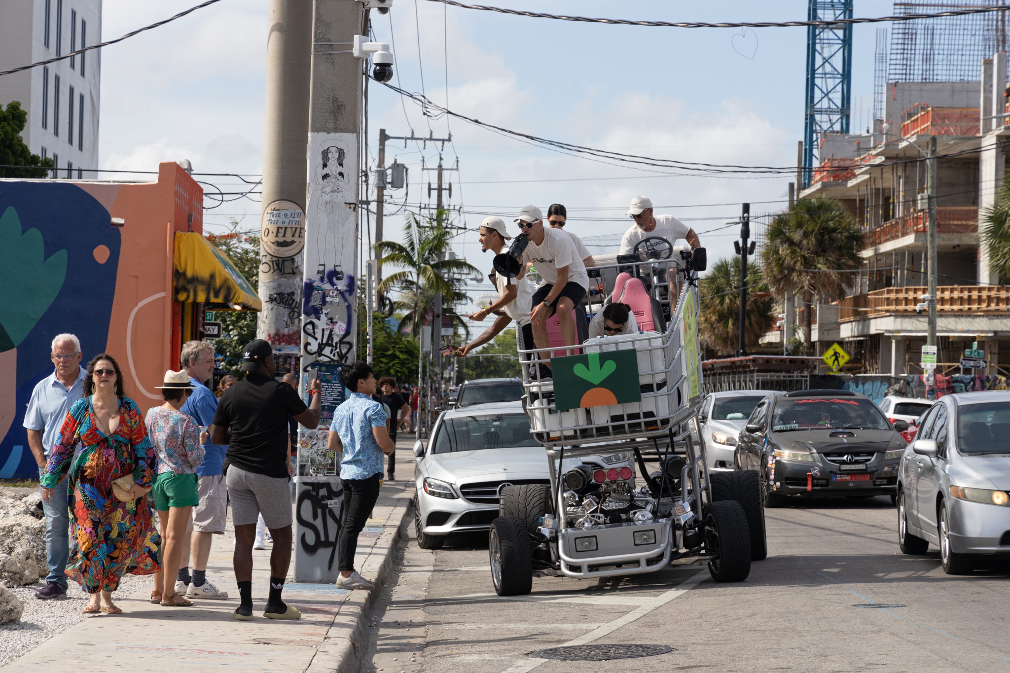 Instacart’s branded shopping-cart rig — a life-size green-carrot cart with Instacart riders aboard — rolling in traffic on a Miami street, July 2022