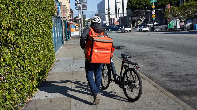 A DoorDash delivery driver with a red delivery bag