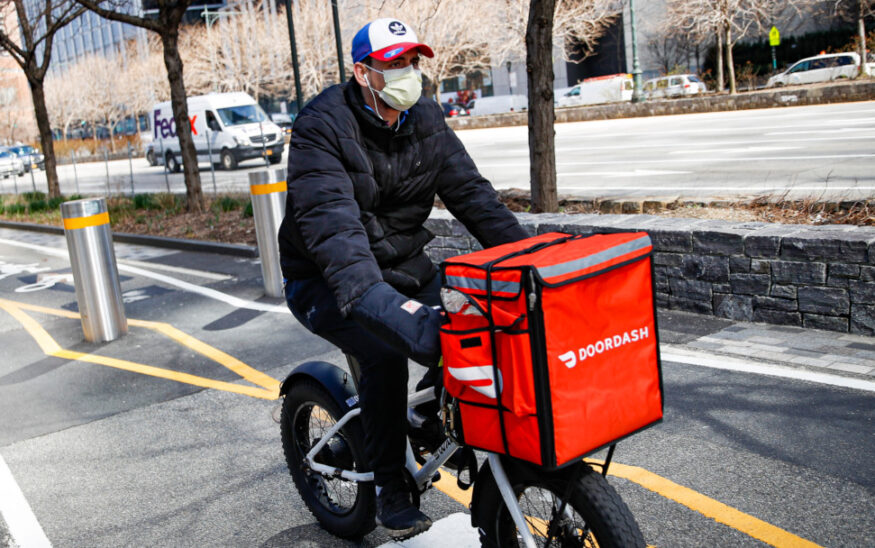 A DoorDash delivery driver on a bike in the city