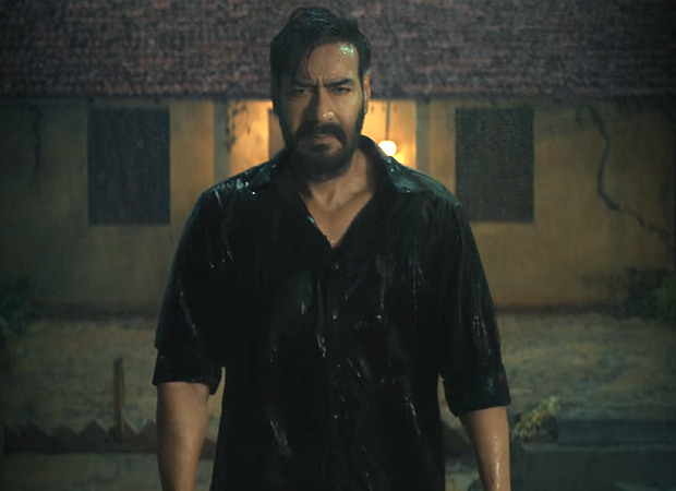 Ajay Devgn as Vijay Salgaonkar, standing in the rain outside a house at night in Drishyam: The Conclusion.