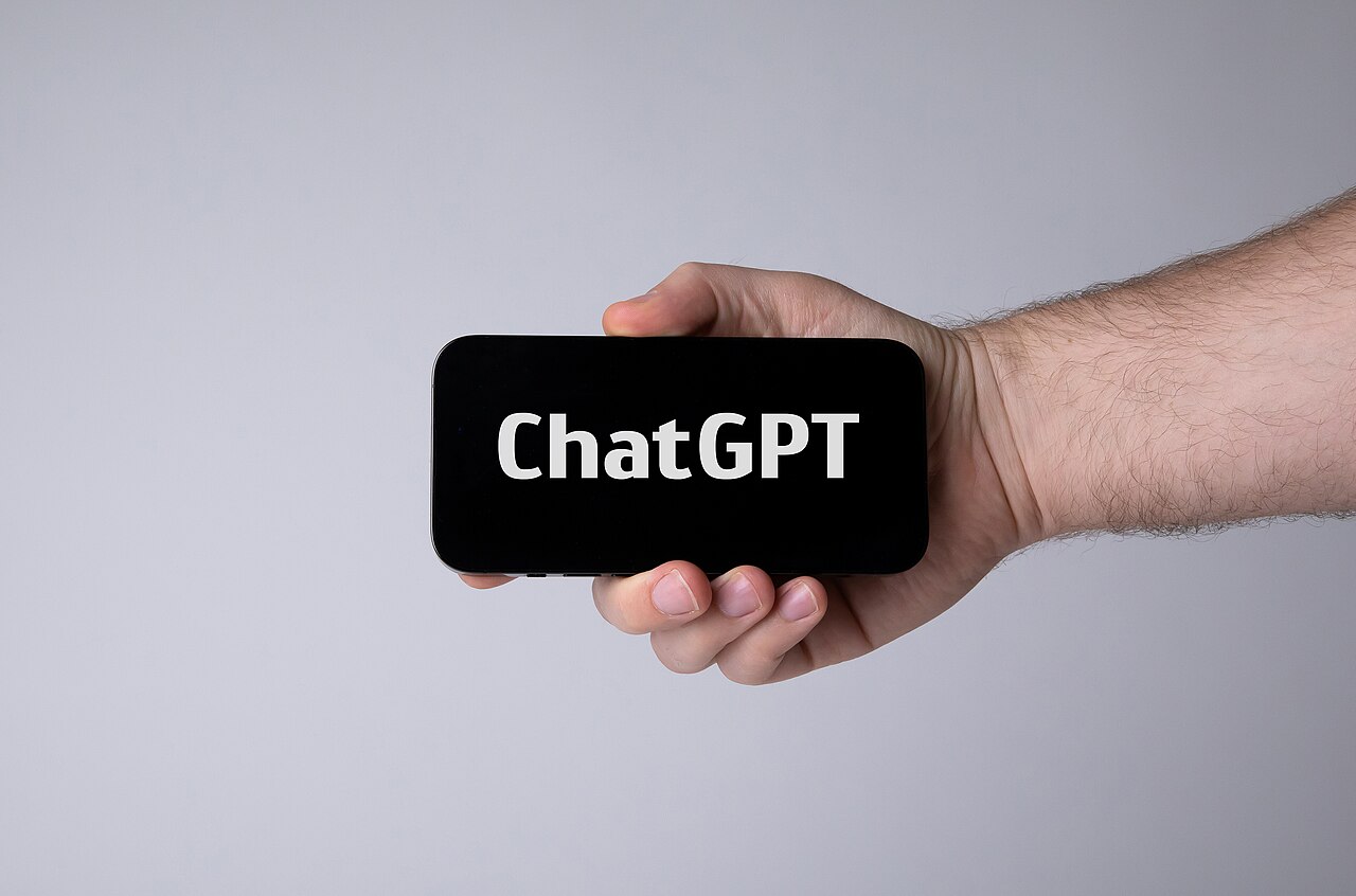 A hand holding a smartphone displaying ChatGPT