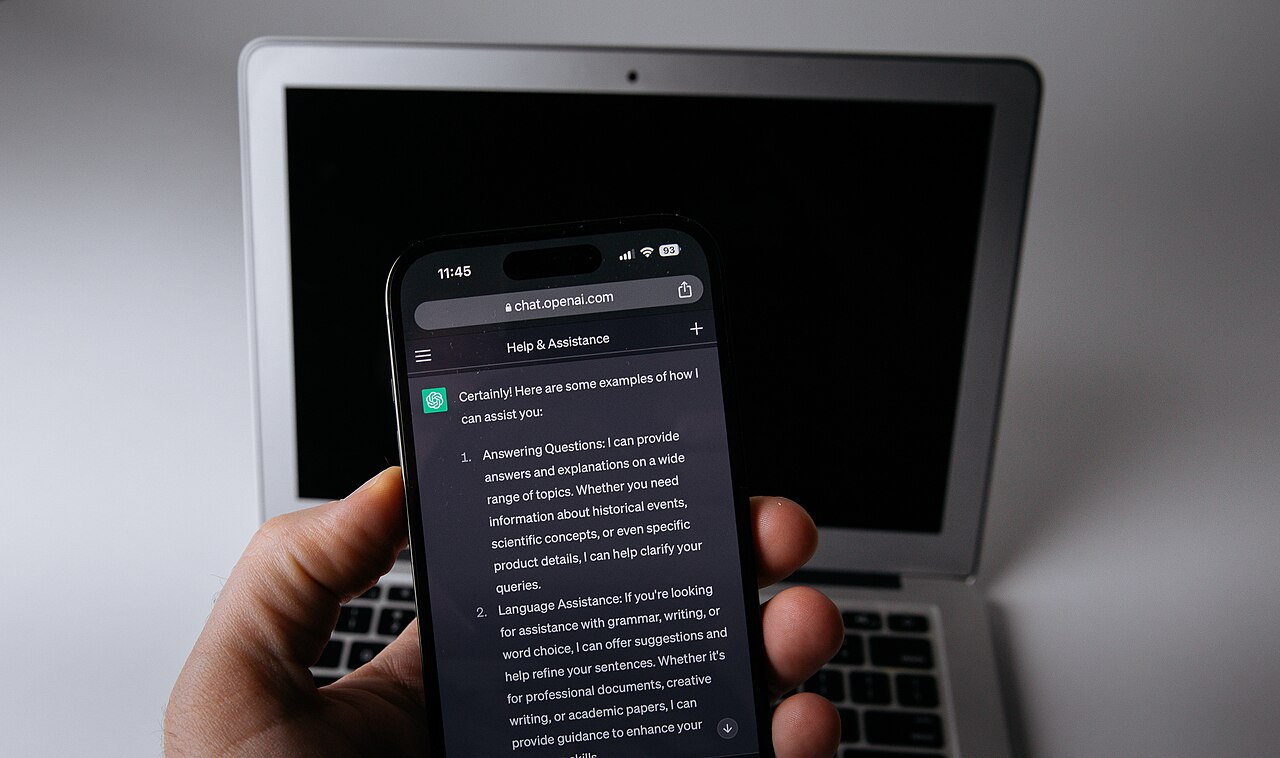 A smartphone showing the ChatGPT app next to a laptop