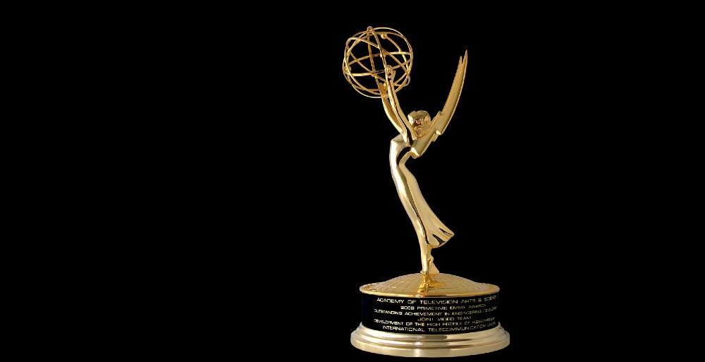 A gold Emmy statuette on a black background, winged figure holding an atom aloft