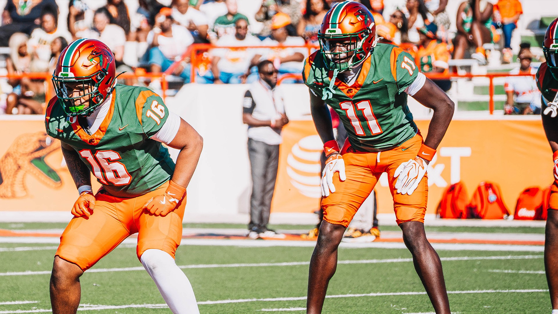 Florida A&M Rattlers football players in green jerseys and orange pants set on the field at Bragg Memorial Stadium
