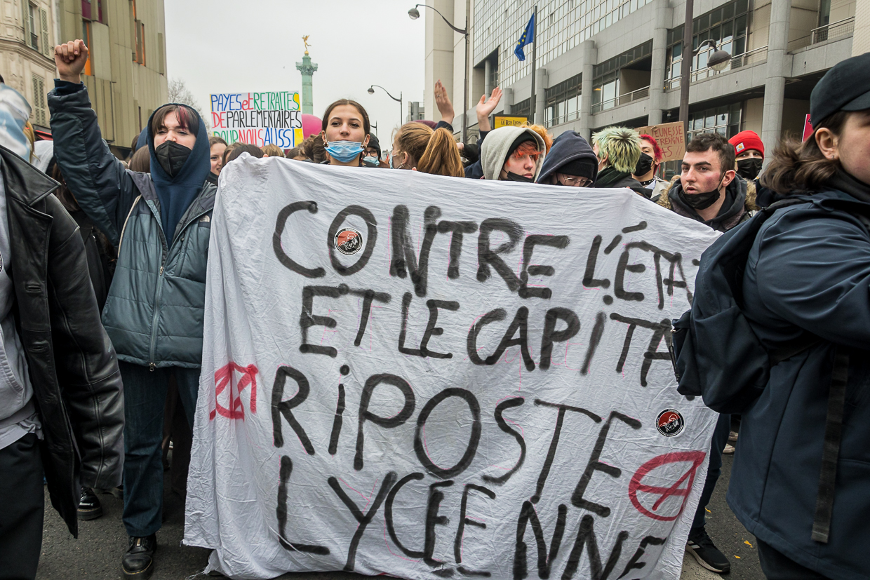 Protesters hold a banner reading Contre l’État et le capitalisme, riposte lycéenne at Place de la Bastille in Paris