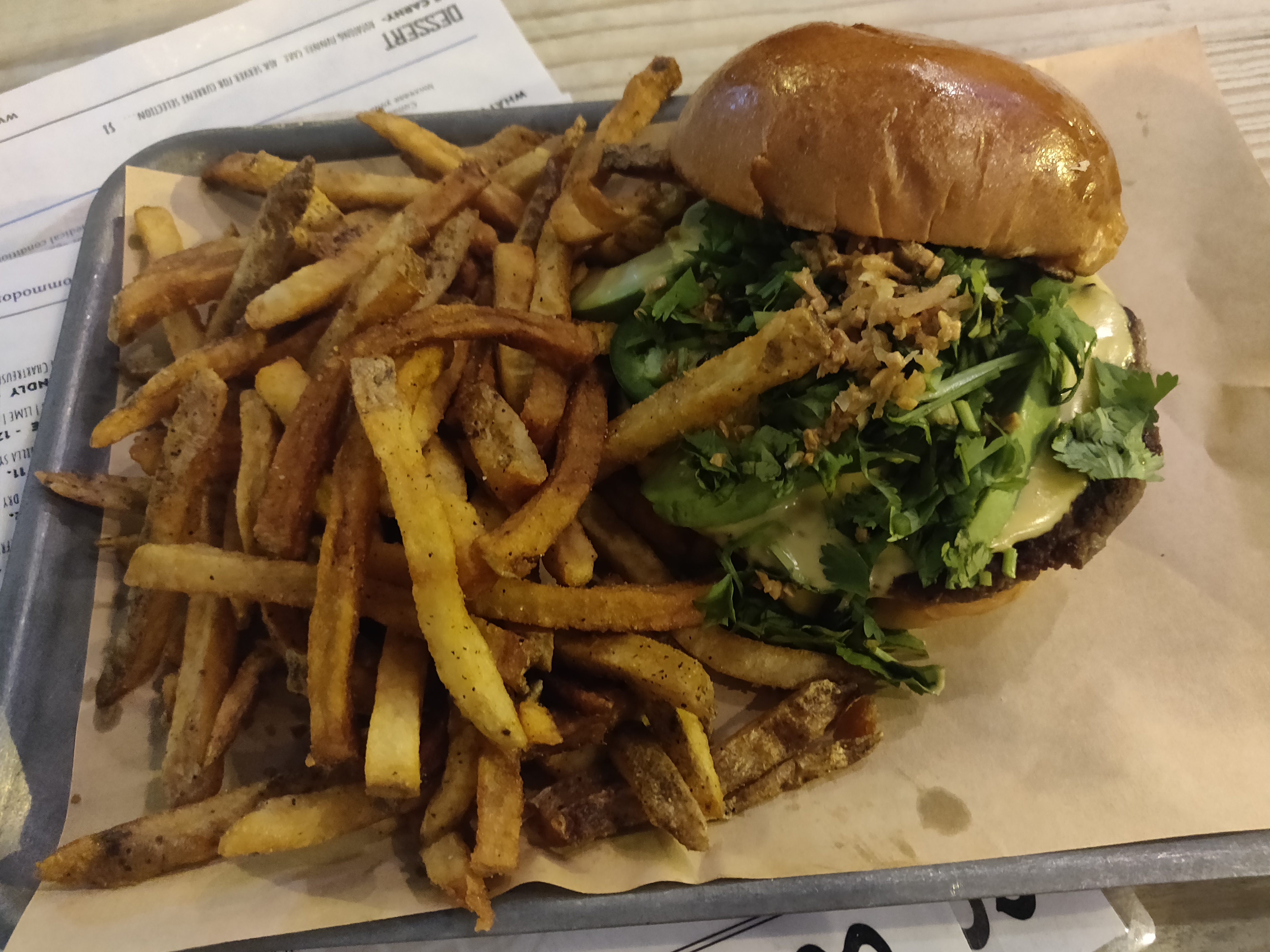 A cheeseburger with fries on a tray, in the style of the smash burgers trending in Paris