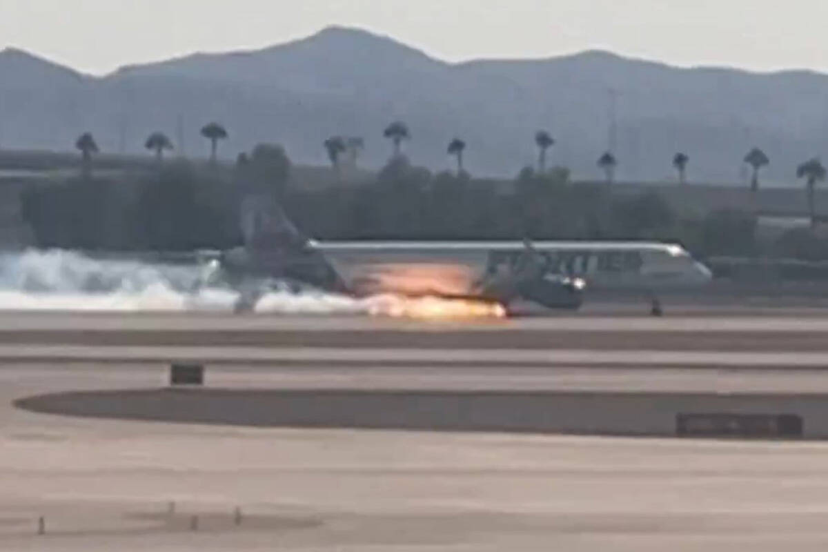 Flames and smoke pour from a Frontier Airlines plane on the runway at Harry Reid International Airport
