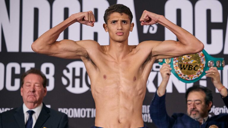 Sebastian Fundora flexes on the scale at the official weigh-in in Las Vegas, his WBC super welterweight championship belt held up behind him