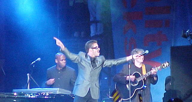 George Michael performing live on stage, arms raised, at the Equality Rocks concert in Washington, D.C.