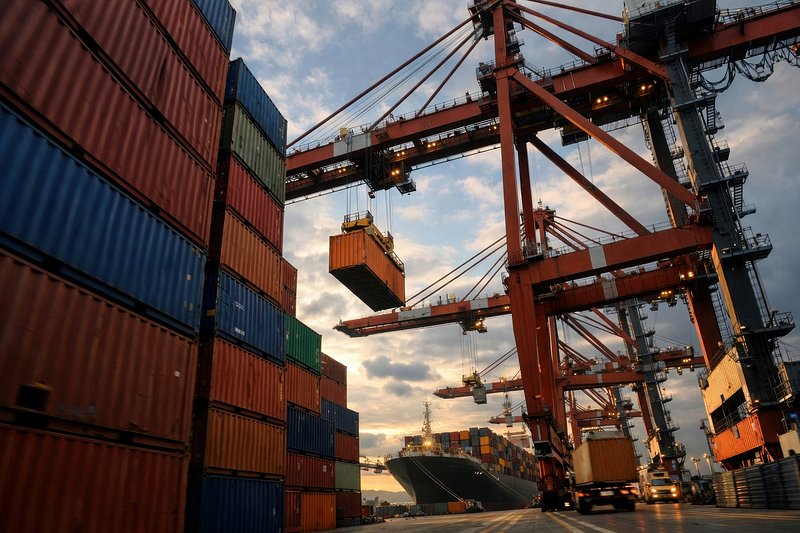 A container ship being loaded by cranes at a shipping port
