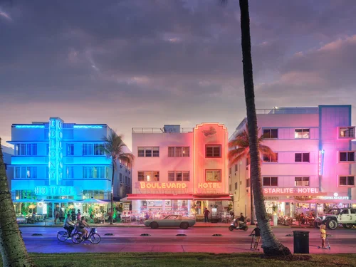 Ocean Drive in Miami Beach lit up at dusk, the kind of sun-soaked strip Rockstar is satirizing in GTA 6