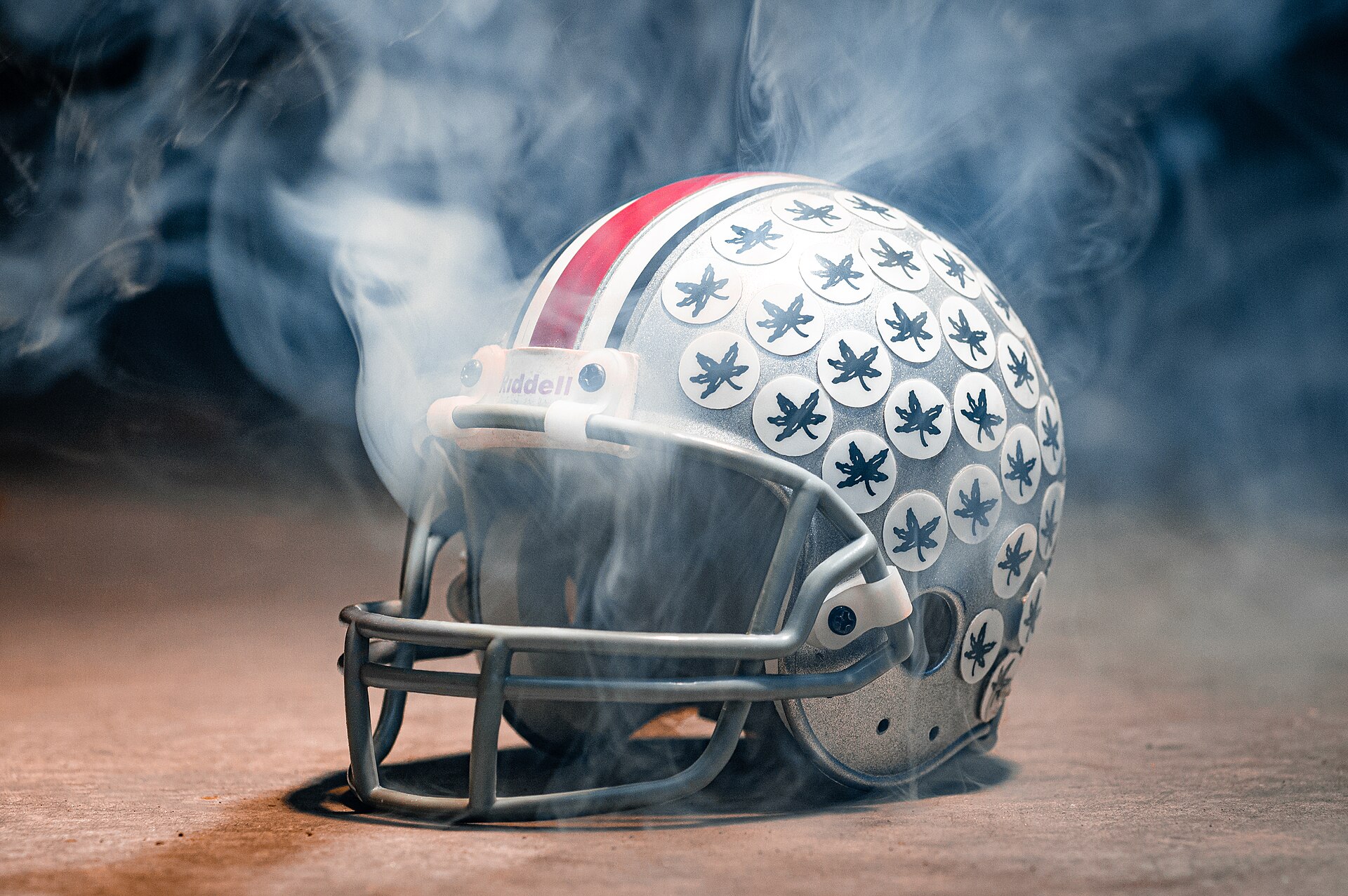 An Ohio State Buckeyes helmet covered in Buckeye leaf stickers, wreathed in smoke