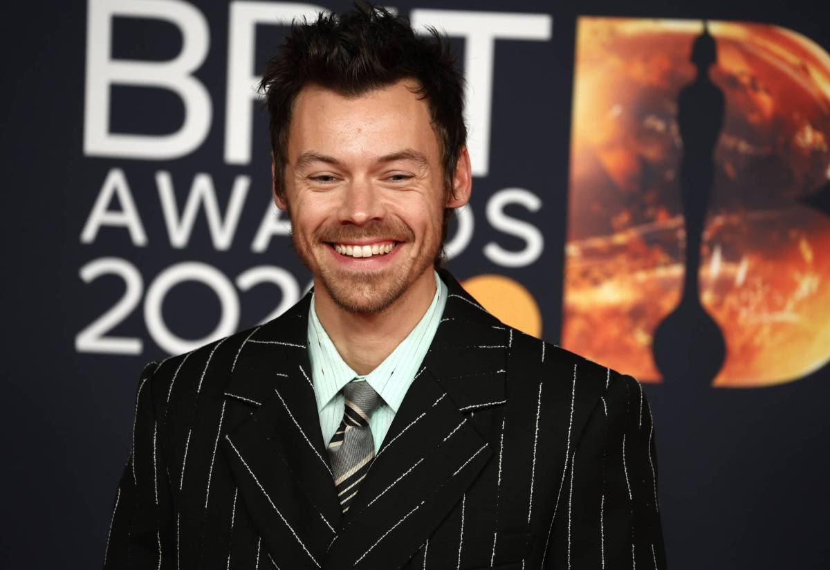 Harry Styles smiling in a pinstripe suit at a red-carpet event