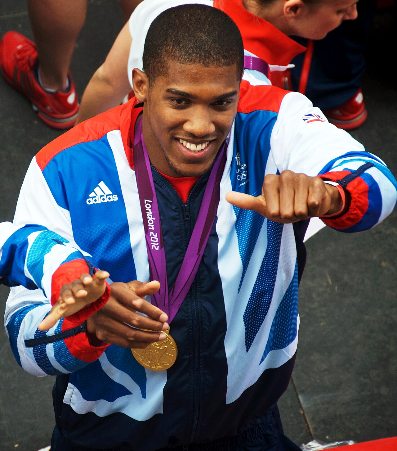 Anthony Joshua with the London 2012 Olympic gold medal — the bar that separates the entertainment lane from the sport. Collins never pretended otherwise.